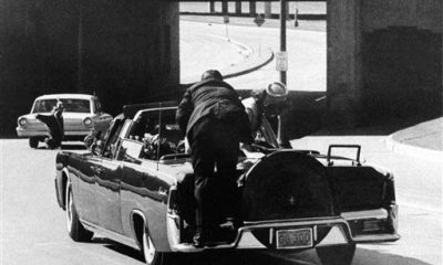 FILE - In this Nov. 22, 1963 file photo, President John F. Kennedy slumps down in the back seat of the Presidential limousine as it speeds along Elm Street toward the Stemmons Freeway overpass after being fatally shot in Dallas. Mrs. Jacqueline Kennedy leans over the president as Secret Service agent Clinton Hill rides on the back of the car. (AP Photo/Ike Altgens, File)