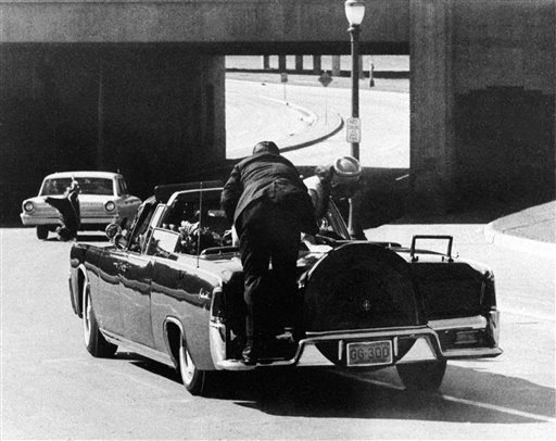 FILE - In this Nov. 22, 1963 file photo, President John F. Kennedy slumps down in the back seat of the Presidential limousine as it speeds along Elm Street toward the Stemmons Freeway overpass after being fatally shot in Dallas. Mrs. Jacqueline Kennedy leans over the president as Secret Service agent Clinton Hill rides on the back of the car. (AP Photo/Ike Altgens, File)