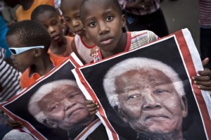 South African children hold placards showing the face of Nelson Mandela as they celebrate his life.