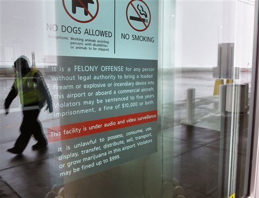 A security officer walks near a notice prohibiting marijuana possession at Denver International Airport, Monday, Jan. 27, 2014. (AP Photo/Brennan Linsley)