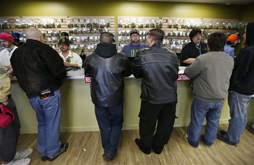 In this Jan. 1, 2014 file photo, employees help customers at the crowded sales counter inside the Medicine Man marijuana retail store, in Denver. A group of marijuana activists want another pot vote in Colorado, to loosen restrictions on who can have it. A proposed ballot measure up for state review Wednesday Jan. 14, 2014 would end criminal penalties for cannabis possession. If approved, the measure would effectively discard Colorados 1-ounce possession limit and 21-and-over restriction. (AP Photo/Brennan Linsley, File)