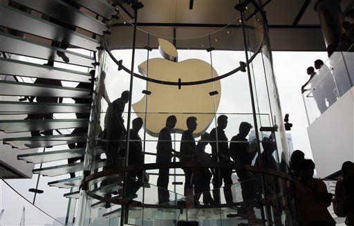 In this Sept. 24, 2011, file photo, customers walk past a huge Apple logo at the new store which is located on two floors linked by a glass spiral staircase in Hong Kong's upscale International Financial Center Mall. Friday, January 24, 2014, marks thirty years after the first Mac computer was introduced, sparking a revolution in computing and in publishing as people began creating fancy newsletters, brochures and other publications from their desktops. (AP Photo/Kin Cheung)