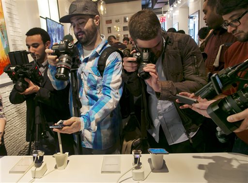Photographers swarm around a Samsung Galaxy S5 smartphones, left,  and Samsung Gear 2's at the Samsung Galaxy Studio, in New York,  Monday, Feb. 24, 2014. (AP Photo/Richard Drew)