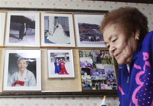n this Feb. 3. 2014, Kim Gun-ja, 89, former comfort woman who was forced to serve for the Japanese troops as a sex slave during World War II, passes by her wedding picture, top center, at the House of Sharing, a nursing home and museum for 10 former sex slaves, in Toechon, South Korea. (AP Photo/Ahn Young-joon)