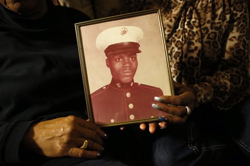 In this March 12, 2014 photo, a picture of Jerome Murdough is held by his mother Alma Murdough left, and sister  Cheryl Warner at Alma  Murdough's home in the Queens borough of New York.  Jerome Murdough, a mentally ill, homeless former Marine arrested for sleeping in the roof landing of a New York City public housing project during one of the coldest recorded winters in city history, died last month in a Rikers Island jail cell that multiple city officials say was at least 100 degrees when his body was discovered.  Murdough, 56, was found dead in his cell in a mental observation unit  in the early hours of Feb. 15, after excessive heat, believed to be caused by an equipment malfunction, redirected its flow to his upper-level cell, the officials said.  (AP Photo/Jason DeCrow)
