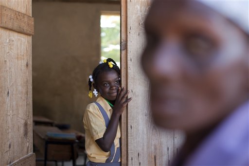 In this Tuesday, March 25, 2014 photo, Brenia Petit-Jean, 12, looks out from a classroom while her mother queues for food donated by the U.N. World Food Program, WFP, at a local school in Bombardopolis, northwestern Haiti. (AP Photo/Dieu Nalio Chery)
