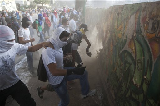 Demonstrators destroy a wall in order to have more rocks to throw at the Bolivarian National Guard during anti-government protests in Caracas, Venezuela, Tuesday, March 4, 2014. A year after the death of Hugo Chavez, Venezuela has been rocked by weeks of violent protests that the government says have left 18 dead. (AP Photo/Rodrigo Abd)