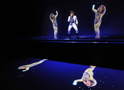 Janelle Monae, center, performs alongside holograms of M.I.A. during a launch party for the Audi M3 on Thursday, April 3, 2014 in West Hollywood, Calif. (Photo by Chris Pizzello/Invision/AP)