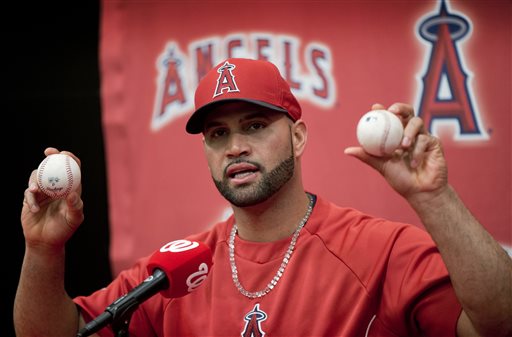 Los Angeles Angels Albert Pujols holds up the balls that he hit for his 499th, right, and 500th, left, career homers during a new conference following a baseball game against the Washington Nationals, Tuesday, April 22, 2014 in Washington. The Angels won the game 7-2. (AP Photo/Pablo Martinez Monsivais)
