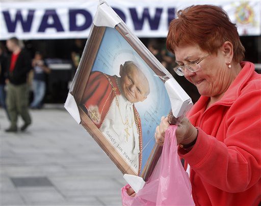 A woman places her just-purchased portrait of Pope John Paul II into a carrier bag in the pontiffs hometown of Wadowice, Poland, on Saturday, April 26, 2014, on the eve of Polands beloved pontiff being made a saint in a Vatican ceremony. Wadowice and nearby Krakow are among the key places linked to John Paul in Poland that are holding observances to mark the occasion. People will be able to see the Vatican ceremony live on giant screens there, and in many other places in Poland. (AP Photo/Czarek Sokolowski)