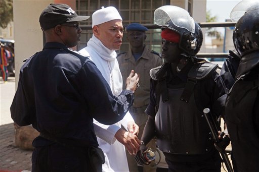 In this Friday, March 15, 2013 file photo, Karim Wade, center, the son of former Senegalese President Abdoulaye Wade, is blocked by police as he tries to approach journalists and gathered supporters outside the office of the special prosecutor investigating him on charges of embezzled funds, in Dakar, Senegal. (AP Photo/File)