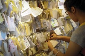 A woman ties a message card for passengers onboard the missing Malaysia Airlines Flight 370 at a shopping mall in Petaling Jaya, near Kuala Lumpur, Malaysia, Thursday, April 10, 2014.(AP Photo)