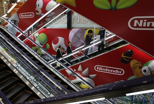 Shoppers take escalators under the logo of Nintendo and Super Mario characters at an electronics store in Tokyo Wednesday, May 7, 2014. Nintendo Co. sank to a loss for the fiscal year ended March as sales of its Wii U game machine continued to lag, but the Japanese manufacturer of Pokemon and Super Mario games promised Wednesday to return to profit this year. (AP Photo/Shizuo Kambayashi)
