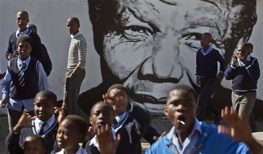 Schoolchildren who had just paid a visit to the former house of the late South African President Nelson Mandela, walk past a mural of Mandela in the Soweto township of Johannesburg, South Africa Friday, May 9, 2014. Vote-counting in elections in South Africa is almost complete, indicating a comfortable win for the ruling African National Congress but also a strengthening of key opposition rivals that promised change after 20 years of leadership by the party that led the fight against apartheid. (AP Photo/Ben Curtis)