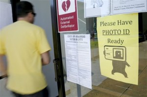 In this May 5, 2014 file photo, a voter walks past a "Please Have Photo ID Ready" sign as he enters an early-voting polling place in downtown Little Rock, Ark. The Arkansas Supreme Court has tossed out a judge's ruling striking down the state's voter ID law, but stopped short of ruling on the constitutionality of the measure. (AP Photo/Danny Johnston, File)