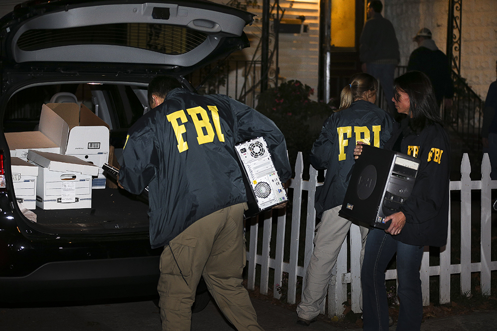 FBI agents remove evidence from the Brooklyn residence of Rabbi Mendel Epstein during an investigation on Oct. 10, 2013, in New York. (AP Photo/John Minchillo)