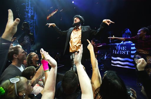 In this photo taken May 16, 2014, Macklemore of the group Macklemore & Ryan Lewis strikes a pose as he performs "Thrift Shop" to a mob of waving fans during Vivid: Spectacle Opening Night Party at the EMP Museum in Seattle. (AP Photo/The Seattle Times, Lindsey Wasson)