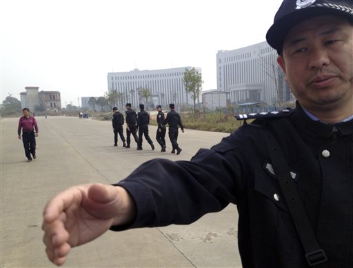 In this Oct. 28, 2013 file photo, a Chinese police officer reaches out towards a journalist outside the courthouse where a trial of Chinese activists from a group that urges fellow citizens to embrace their constitutional rights is underway in Xinyu city in eastern China's Jiangxi province. (AP Photo/Aritz Parra, File)