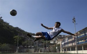 In this June 17, 2014 photo, Andre Rodrigues de Principe, 14, known as Andrezinho to his neighbors, kicks the ball during his practice session in the Vidigal slum of Rio de Janeiro, Brazil. Although hes trained with two of Brazils premier teams, Fluminense and Vasco da Gama, hes currently only playing for his local squad comprised of other kids from his Vidigal favela, as slums here are known. (AP Photo/Leo Correa)