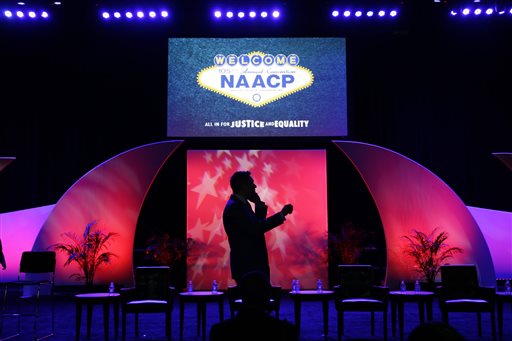 A man speaks on a phone on stage after a panel discussion on black turnout for midterm elections and voter suppression during the NAACP annual convention Tuesday, July 22, 2014, in Las Vegas. (AP Photo/John Locher)