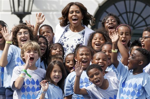 First lady Michelle Obama, a longtime supporter of healthier eating and physical fitness, is surrounded by children as she expands her push for America to drink more water, at a "Drink Up" event at the White House in Washington, Tuesday, July 22, 2014. Obama launched the campaign with the Partnership for a Healthier America to encourage people to drink plain water more often.  (AP Photo/J. Scott Applewhite)