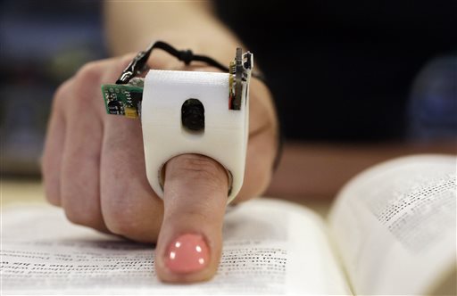 In this Thursday, June 26, 2014 photo, a model wears a FingerReader ring at the Massachusetts Institute of Technology's Media Lab in Cambridge, Mass. Researchers designed and developed the instrument, which enables people with visual disabilities to read text printed on paper or electronic devices. (AP Photo Stephan Savoia)