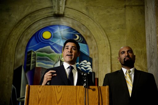 Denver City Attorney Scott Martinez, left, and Qusair Mohamedbhai, representing Jamal Hunter, give a news conference in Denver on Tuesday, July 22, 2014 about a settlement reached by both sides in the amount of $3.25 million. The federal jail-abuse lawsuit was filed by Hunter, a former inmate who said a deputy ignored his screams while a group of fellow inmates brutally beat him and scalded his genitals with hot water. (AP Photo/The Denver Post, AAron Ontiveroz)