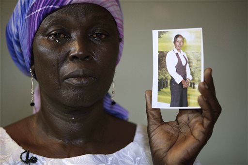In this Monday, May 19, 2014 file photo, Martha Mark, the mother of kidnapped school girl Monica Mark cries as she displays her photo, in the family house, in Chibok, Nigeria. (AP Photo/Sunday Alamba, File)