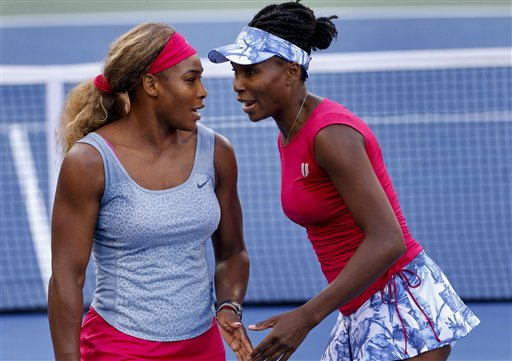 Serena Williams, left, and Venus Williams talk between points against Timea Babos and Kristina Mladenovic during a doubles match at the 2014 U.S. Open tennis tournament, Thursday, Aug. 28, 2014, in New York. (AP Photo/Matt Rourke)