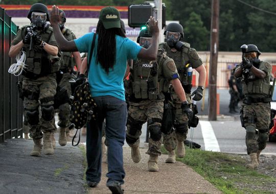 Police wearing riot gear point their weapons before arresting a man Aug. 11, 2014, in Ferguson, Mo. (Jeff Roberson/AP Photo)