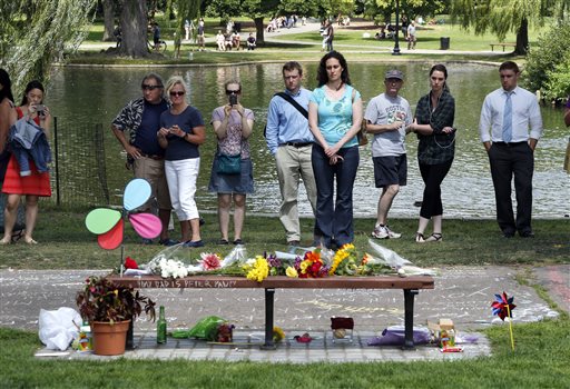 People pause by a bench at Boston's Public Garden, Tuesday, Aug. 12, 2014, where a small memorial has sprung up at the place where Robin Williams filmed a scene during the movie, "Good Will Hunting." Williams, 63, died at his San Francisco Bay Area home Monday in an apparent suicide. (AP Photo/Elise Amendola)