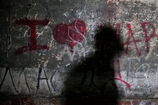 In this Aug. 26, 2014 photo, the shadow of a migrant is seen on the wall of a train depot in the town of Chahuites, Mexico, which has decided to protect and aid migrants passing through. Town officials say they do not allow federal police raids on migrants to happen in their small municipality. Local police, tasked with protecting migrants passing through town, stood watch along the tracks near migrants resting and sleeping outdoors. (AP Photo/Rebecca Blackwell)