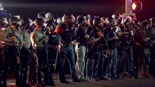 Police in riot gear mobilize during a standoff with protesters Monday, Aug. 18, 2014, during a rally for Michael Brown, who was killed by a police officer Aug. 9 in Ferguson, Mo. Brown's shooting has sparked more than a week of protests, riots and looting in the St. Louis suburb. (AP Photo/Charlie Riedel)