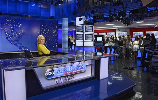 In this Wed., Aug. 27, 2014 photo provided by ABC, the staff gathers at ABC News headquarters for Diane Sawyer, left, who signed off on her last broadcast as anchor of "World News," in New York. Sawyer told viewers that it has been wonderful to be the "home port" of the network's news team each weeknight. She will be replaced next week by David Muir.  (AP Photo/ABC, Ida Mae Astute)
