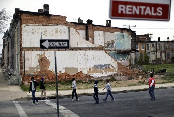 In this April 4, 2013, file photo, a group of boys walk past a partially collapsed row house in Baltimore. The nation’s poverty rate stood still at 15 percent in 2012, the sixth straight year that it has failed to improve. The Census Bureau reported Tuesday, Sept. 17, 2013, that 46.5 million Americans were living in poverty in 2012. (AP Photo/Patrick Semansky)
