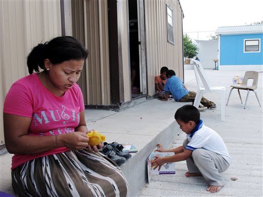 This Aug. 4, 2014 photo shows Eneyda Alvarez of Honduras peeling a mango while her son Antony plays at the Senda de Vida migrant shelter in Reynosa, Mexico. Alvarez hopes to join the thousands of families _ mothers or fathers with young children _ who have crossed the Rio Grande into the U.S. United States. (AP Photo/Christopher Sherman)