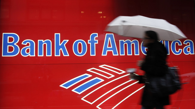 In this Dec. 7, 2011 photo, a woman passes a Bank of America office branch, in New York. Bank of America said Jan. 19, 2012, it made $2 billion in the last three months of 2011 from selling its stake in a Chinese bank and selling debt. That offset losses and higher legal expenses in its mortgage business. (AP Photo/Mark Lennihan)