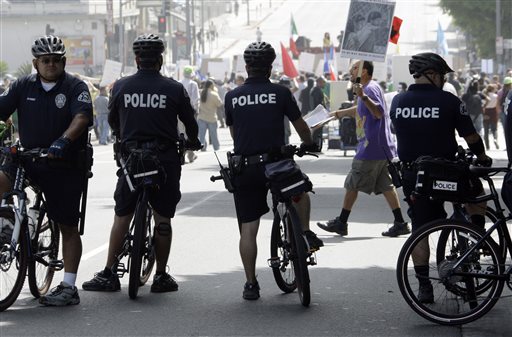 In this Sept. 18, 2010 file photo, officers on bicycles keep watch as demonstrators protesting several incidents of alleged Los Angeles Police Department brutality, including the fatal shooting of Manuel Jamines a month ago, stand outside the LAPD's Rampart Station in the Westlake district of Los Angeles. Police departments across the U.S. are using technology to try to identify problem officers before their misbehavior harms innocent people, embarrasses their employer, or invites a costly lawsuit,  from citizens or the federal government.  The Los Angeles Police Department agreed to set up their $33 million early warning systems after the so-called Rampart scandal in which an elite anti-gang unit was found to have beaten and framed suspected gang members. The system was then implemented in 2007. (AP Photo/Reed Saxon)