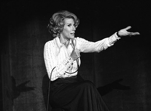 In this Aug. 13, 1975 photo released by the Las Vegas News Bureau, comedian Joan Rivers performs at the MGM in Las Vegas, Nev. Rivers, the raucous, acid-tongued comedian who crashed the male-dominated realm of late-night talk shows and turned Hollywood red carpets into danger zones for badly dressed celebrities,  died Thursday, Sept. 4, 2014. She was 81. Rivers was hospitalized Aug. 28, after going into cardiac arrest at a doctor's office. (AP Photo/Las Vegas News Bureau)