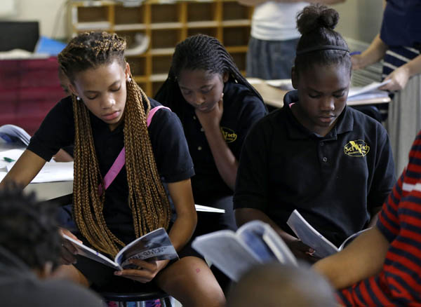 Sixth grade students Miracle Roberson, left, Darion James, and Brianetay Martin, right, read during literature intervention class at ReNEW SciTech Academy, a charter school in New Orleans, Thursday, Aug. 14, 2014. (AP Photo/Gerald Herbert)
