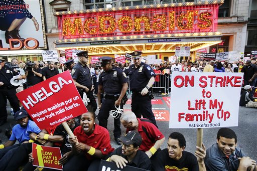 Protesters sit in front of a McDonald's restaurant on 42nd Street in New York's Times Square as police officers move in to begin making arrests, Thursday, Sept. 4, 2014. The protesters are seeking to get pay increases to $15 per hour. Thursday's demonstration is part of a day of planned protests in 150 cities across the country by workers from fast-food chains. (AP Photo/Mark Lennihan)