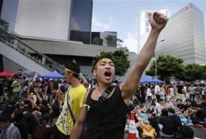 A pro-democracy activist shouts slogans on a street near the government headquarters where protesters have made camp, Wednesday, Oct. 1, 2014 in Hong Kong. Holiday crowds swelled into the tens of thousands as student leaders met with other pro-democracy protesters Wednesday to thrash out a strategy for handling the government's rejection of their demands that the city's top leader resign and Beijing revise its plans to limit political reforms. (AP Photo/Wong Maye-E)