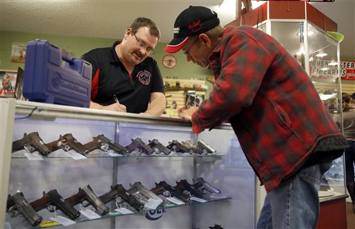 In this Saturday, Nov. 15, 2014 photo, Steven King, left, fills out paperwork while selling a handgun to Dave Benne at Metro Shooting Supplies, in Bridgeton, Mo. Benne, a resident of Florissant, Mo., near Ferguson, said the upcoming grand jury decision on whether to indict police officer Darren Wilson prompted the purchase of his first gun. (AP Photo/Jeff Roberson)