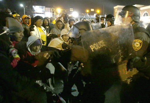 Police officers confront protesters Tuesday, Nov. 25, 2014, in Ferguson, Mo. Missouri's governor ordered hundreds more state militia into Ferguson on Tuesday, after a night of protests and rioting over a grand jury's decision not to indict police officer Darren Wilson in the fatal shooting of Michael Brown, a case that has inflamed racial tensions in the U.S. (AP Photo/David Goldman)