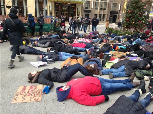 About 200 people demonstrate at a plaza near the historic water tower, located along Chicago's Michigan Avenue, on Friday, Nov. 28, 2014, in Chicago. The protestors called on people to boycott shopping on Black Friday as a show of solidarity with protesters in Ferguson Missouri. At one point the demonstrator lay down on the cold ground in a silent protest. (AP Photo/Sara Burnett)