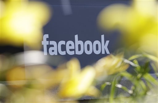 This Friday, May 18, 2012, file photo shows Facebook's headquarters behind flowers in Menlo Park, Calif. Facebook is stepping up its efforts to fight Ebola by adding a button designed to make it easier for its users to donate to charities battling the disease. (AP Photo/Paul Sakuma, File)
