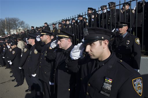 Police officers salute as the hearse of New York city police officer Rafael Ramos drives along his funeral procession route in the Glendale section of Queens, Saturday, Dec. 27, 2014, in New York. Ramos and his partner, officer Wenjian Liu, were killed Dec. 20 as they sat in their patrol car on a Brooklyn street. The shooter, Ismaaiyl Brinsley, later killed himself. (AP Photo/John Minchillo)