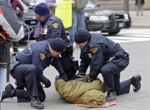 In this Nov. 25, 2014 file photo, police arrest a demonstrator protesting against the shooting of 12-year-old boy Tamir Rice, who was fatally shot by a police officer in Cleveland. The revelation that Cleveland police officials didnt review the checkered history of a police officer who fatally shot a 12-year-old boy highlights what some describe as an unnerving truth about policing -- theres no universal standard for how deeply a department should dig into its recruits pasts. (AP Photo/Mark Duncan, file)
