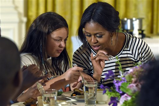 In this Oct. 14, 2014 file photo, first lady Michelle Obama and a student look over their plates as they eat lunch in the East Room of the White House in Washington following the annual fall harvest of the White House Kitchen Garden. House Republicans are making a final push this year to give schools a temporary break from healthier school meal standards. The school meal rules phased in since 2012. (AP Photo/Susan Walsh, File)