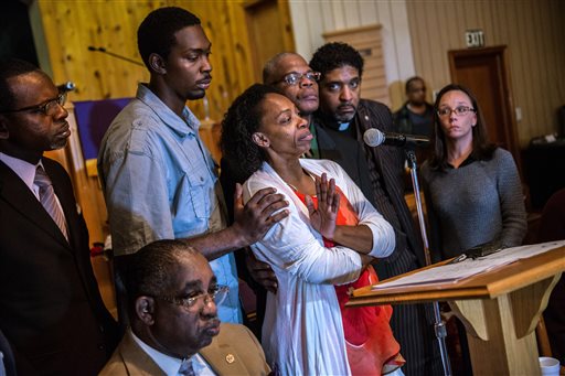 In this Monday, Dec. 1, 2014 photo, Claudia Lacy, center, cries as she thanks the people that showed up at First Baptist Church in Bladenboro, N.C., to listen to the Rev. Dr. William Barber II, president of the North Carolina State Conference of the NAACP, talk about the developments in the investigation of her son's death. Lennon Lacy, a 17-year-old, was found hanging from a swing set in the middle of a trailer park in late August. Surrounding Claudia Lacy are attorney Alan Rogers, left, Wilson Lacy, sitting, Lennon' brother Pierre Lacy, Rev. Gregory D. Taylor, Rev. William Barber II and attorney Heather Rattelade. (AP Photo/The Fayetteville Observer, Raul R. Rubiera) MANDATORY CREDIT